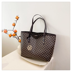 Detail der bedruckten Shopper-Tasche mit M-Monogramm und goldenem Metallanhänger