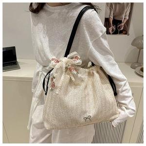 Detail of straw tote bag with lace flower bow and small silver butterfly charm