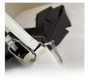 Detail of silver metal buckle connecting the white leather strap to the shoulder bag