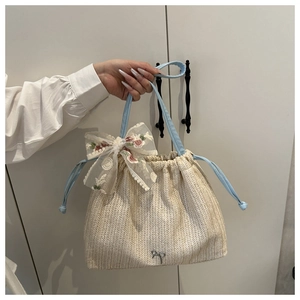 Close-up of woven tote bag with lace bow, floral embroidery and drawstring closure