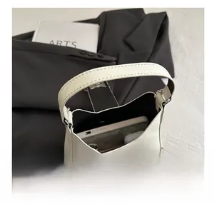 Interior capacity of minimalist cream shoulder bag showing space for phone and earbuds