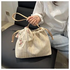 Detail of woven straw bucket bag with floral lace bow and silver butterfly charm