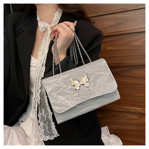 Detail of silver grey handbag with metallic pleated texture and bow chain strap