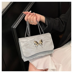 Close-up of light grey wrinkled leather shoulder bag with silver butterfly metal buckle