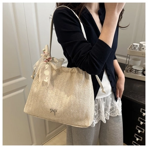 Detail of straw woven tote bag with lace bow scarf and silver butterfly logo