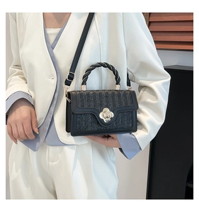 Detailaufnahme der schwarzen gewebten Tasche mit goldenem Blumenverschluss