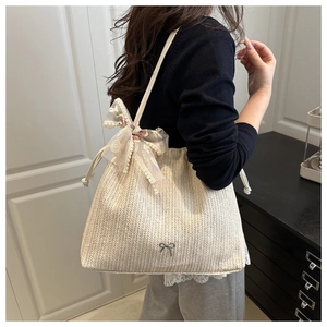 Straw beach tote with lace bow and pink floral embroidery details shown on shoulder