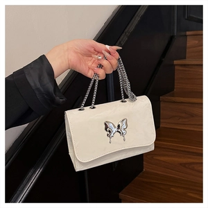 Detail of white leather shoulder bag featuring a silver metal butterfly and chain strap