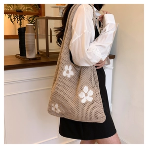 Close-up of khaki crochet tote bag with white floral patterns and hollow knit texture