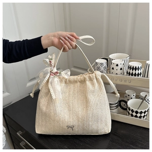 Detail of cream straw tote bag featuring pink floral lace bow and metallic butterfly clasp