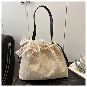Detail of straw woven tote with floral lace bow and metallic butterfly logo