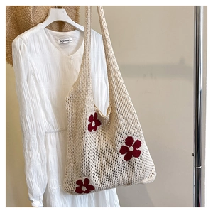Close-up of cream crochet knit tote bag with large red floral pattern and mesh texture