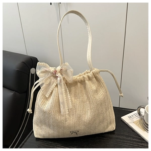 Close-up of straw beach tote with lace flower bow and drawstring closure on a wooden table