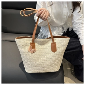 Détail du sac cabas en paille tressée avec bordure en similicuir brun et papillon rose