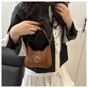 Détail d'un sac baguette marron en cuir vintage avec un nœud métallique argenté