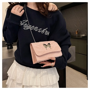 Detail of light pink crossbody bag featuring metallic butterfly buckle and pleated texture
