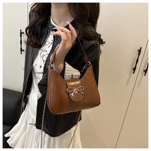 Detail of vintage brown PU leather baguette bag featuring a silver bow buckle and chain