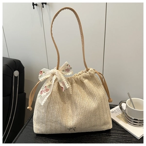 Detail of hand-woven straw tote with silver bow charm and floral lace ribbon detail