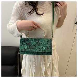 Detail of green crossbody bag with butterfly embroidery and golden metal handle
