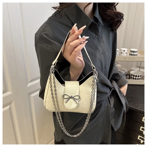 Détail du sac baguette crème minimaliste avec nœud argenté et chaîne en métal épaisse
