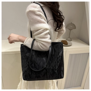 Close-up of black tote bag with unique pleated texture on a shoulder-carried model