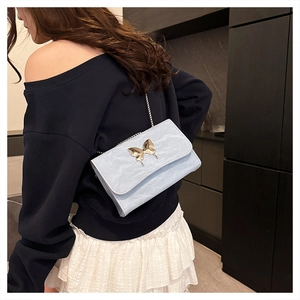 Close-up of light blue pleated leather bag with gold butterfly clasp on model