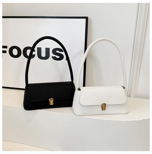 Detail showing woven texture and gold metal locks on black and white shoulder bags