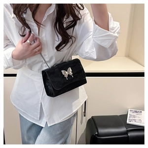 Detail of velvet chain bag with silver butterfly buckle and metallic strap on model