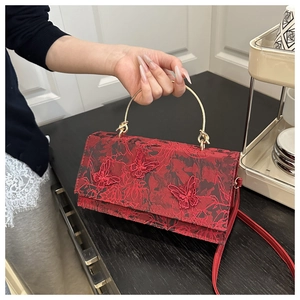 Detail of red crossbody bag featuring floral fabric textures and 3D butterfly embroidery