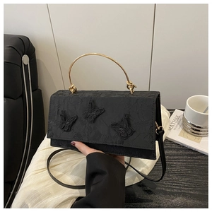 Detailed embroidery of black butterflies on fabric handbag with golden metal handle