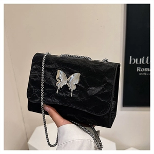 Détail du sac bandoulière plissé noir avec papillon en métal argenté et bandoulière chaîne