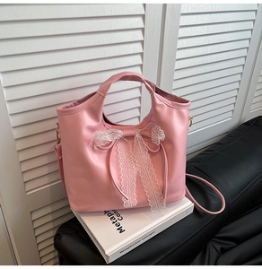 Close-up of pink faux leather bag with white lace bow detail and gold hardware