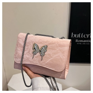 Détail du sac en cuir plissé rose avec ornement papillon en métal et bandoulière chaîne