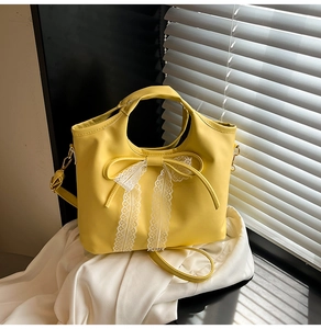 Detail of yellow leather bag with lace bow decoration and gold-tone hardware finish