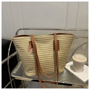 Détail du sac cabas tissé avec broderie de papillon rose et bandoulière en cuir