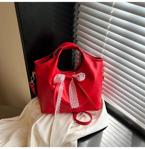 Detail of red leather bucket bag with white lace bow and gold-tone hardware hooks
