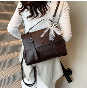 Detail of dark brown leather backpack with white lace bow and beaded pendant charm