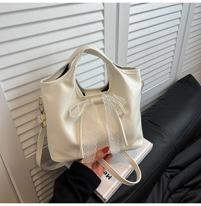 Detail of delicate lace bow on cream white leather tote bag with vintage aesthetic