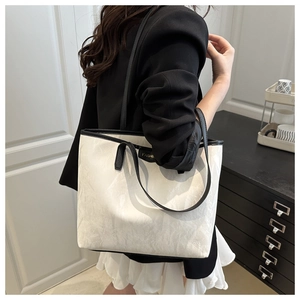 Détail du cabas crème avec plis texturés marbrés et bordures en cuir noir chic
