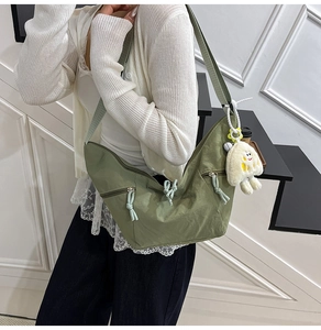 Detail of green crescent nylon bag with zip pockets and white plush cloud charm