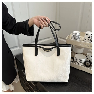 Détail d'un sac cabas blanc avec plis texturés et bordures noires contrastées