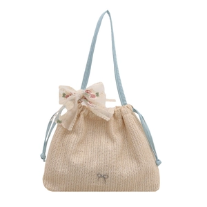 Straw tote bag with white lace bow and light blue straps on a plain white background