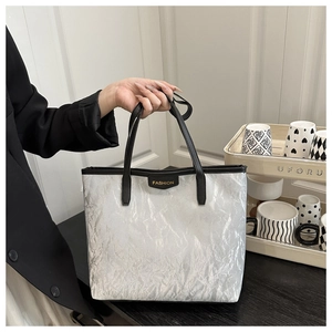 Détail du sac cabas argenté avec texture froissée métallique et poignées noires