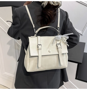 Detail of cream leather backpack with lace bow and pearl charm on a model