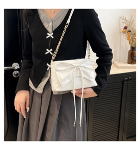 White PU leather shoulder bag with large bow and gold chain strap shown on model