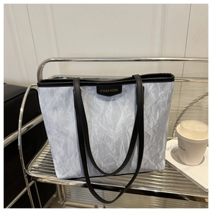 Detail view of large grey tote bag with FASHION label on a modern metal shelf