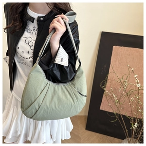 Detail of light green pleated crescent bag with wide fabric strap on a model