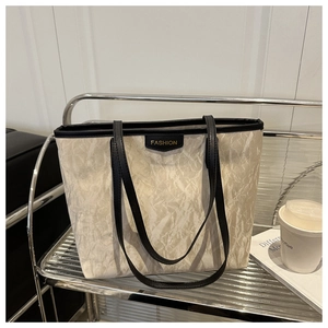 Detail of off-white marbled tote bag with black leather straps on a modern shelf