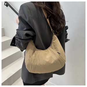 Detail view of khaki pleated nylon crescent bag worn crossbody with a minimalist wide strap