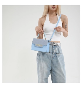 Detail of light blue PU leather crossbody bag with woven texture and gold metal buckle
